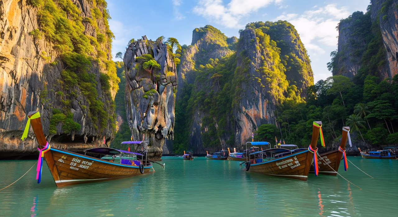 Dlhé člny kotviace pod mohutnými vápencovými útesmi pláže Railay v Krabi
